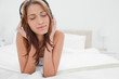 Foto: Redhead woman lying on her belly while listening music Redhead woman lying on her belly while listening music