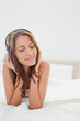 Foto: Smiling woman lying on her belly while listening music Smiling woman lying on her belly while listening music