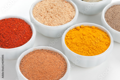 Photo: Different spices in white bowls isolated on white background. Different spices in white bowls isolated on white background.