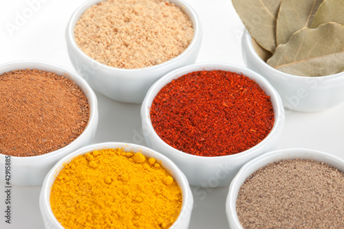Photo: Different spices in white bowls isolated on white background. Different spices in white bowls isolated on white background.