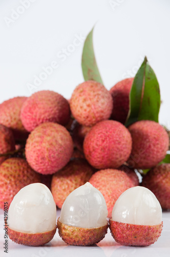 Photo: Fresh lychees with leaves on white background Fresh lychees with leaves on white background