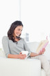 Laughing young woman reading a book with a coffee