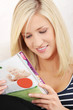 Happy woman is reading colorful magazine.