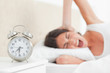 Upset brunette waking up by her alarm 