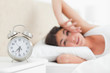 Cute brunette waking up by her alarm 