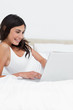 Beaming brunette using her laptop