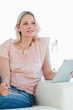 Thoughtful blonde buying online with a touchpad