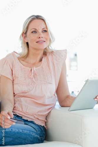 Photo: Thoughtful blonde buying online with a touchpad Thoughtful blonde buying online with a touchpad