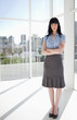 Serious woman in a well-lit room in front of buildings