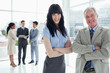 Photo: Two smiling business people standing upright and three executives behind them Two smiling business people standing upright and three executives behind them