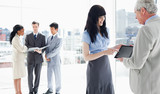 Photo: Three business people looking at files and two others looking at a tablet computer Three business people looking at files and two others looking at a tablet computer