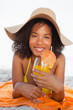 Photo: Young relaxed woman lying down while wearing a straw hat and holding a cocktail Young relaxed woman lying down while wearing a straw hat and holding a cocktail