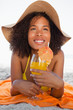 Photo: Young smiling woman in beachwear lying on the beach while drinking a cocktail Young smiling woman in beachwear lying on the beach while drinking a cocktail