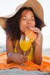 Photo: Young relaxed woman closing her eyes while lying on the beach with a cocktail Young relaxed woman closing her eyes while lying on the beach with a cocktail