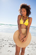 Young happy woman hiding her bikini with her straw hat
