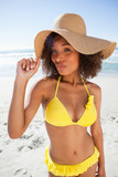 Photo: Young beautiful woman standing up with puckered lips while holding her hat brim Young beautiful woman standing up with puckered lips while holding her hat brim