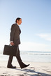 Young businessman walking on the beach