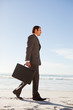 Young handsome businessman walking in front of the ocean