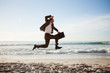 Photo: Young businessman jumping on the beach with his briefcase Young businessman jumping on the beach with his briefcase