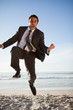 Young businessman shouting while jumping on the beach