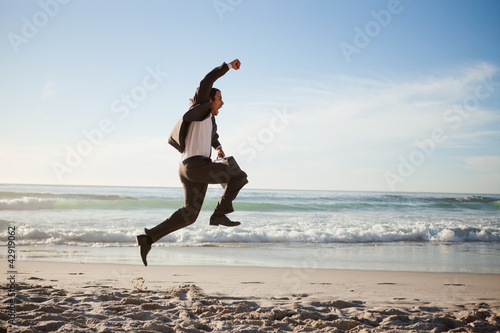 Photo: Successful businessman jumping on the beach Successful businessman jumping on the beach