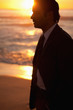 Young businessman standing on the beach at sunset