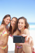 Three women in bikinis pose for a photo