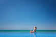 Foto: Beautiful woman sitting near infinity pool and looking to sea an Beautiful woman sitting near infinity pool and looking to sea an