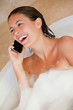 Photo: Laughing woman with her cellphone in the tub Laughing woman with her cellphone in the tub