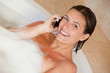 Photo: Smiling woman with her mobile phone in the tub Smiling woman with her mobile phone in the tub