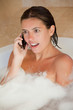 Surprised looking woman with her mobile phone in the tub