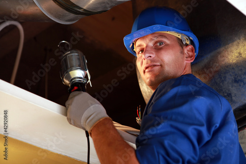 Photo: Electrician looking into a loft space with a lamp Electrician looking into a loft space with a lamp