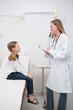 Smiling doctor talking to a smiling girl sitting on a table