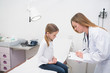 Doctor writing in a notepad in front of a girl sitting