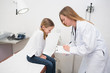 Doctor writing in a notepad in front of a smiling girl sitting