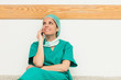 Surgeon smiling while sitting on the floor and phoning