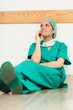 Surgeon sitting on the floor and phoning with her legs crossed