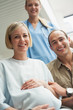 Smiling pregnant woman in a wheelchair with a nurse and a man