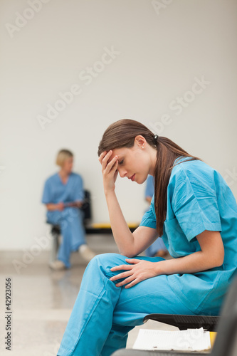 Photo: Sad nurse with a clipboard while sitting in a waiting room Sad nurse with a clipboard while sitting in a waiting room