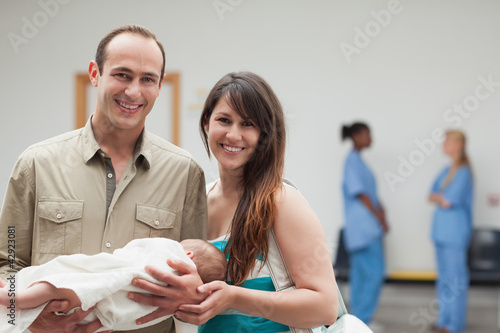 Photo: Smiling couple holding a new born baby Smiling couple holding a new born baby