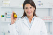 Smiling female pharmacist holding pills and standing in a pharmacy