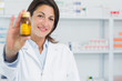 Smiling female pharmacist showing pills and standing in a pharmacy