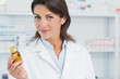 Female pharmacist holding a bottle of pills in a pharmacy