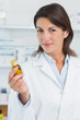 Happy female pharmacist holding a bottle of pills in a pharmacy
