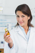 Smiling female pharmacist holding a bottle of pills in a pharmacy