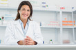 Smiling woman pharmacist behind a counter joining her hands