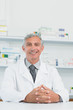 Smiling male pharmacist with his hands joined on a counter