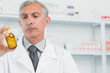 Male pharmacist looking at a flask of pills