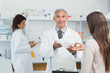 Pharmacist in a drugstore giving a bag of pills to a female client