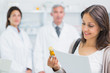 Female customer holding a paper and pills while standing in a pharmacy